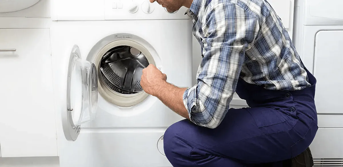 Handyman inspecting a dryer drum and internal parts for repair in San Diego, CA