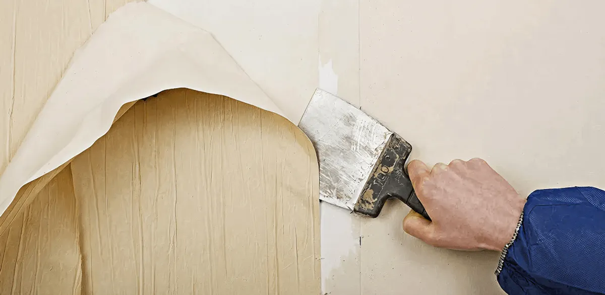Handyman removing wallpaper with a scraper for wall preparation in San Diego, CA