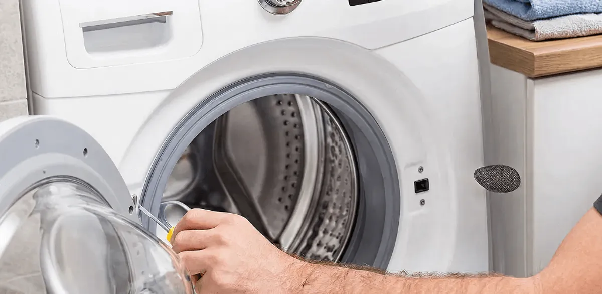 Handyman repairing a front-load washing machine and inspecting the drum in San Diego, CA